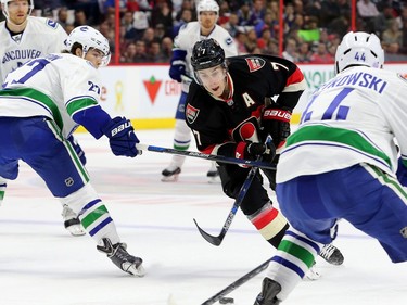 Kyle Turris races for the puck through a wall of Vancouver players.