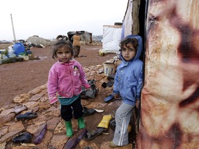 Umm Ali's children who fled the violence in the northern Syrian city of Aleppo, play at the entrance of their tent at an unofficial refugee camp in Jabaa, a village in the Bekaa Valley in Lebanon on December 20, 2014. With just blankets to shield them against the icy wind and rain tens of thousands of Syrian refugees in Lebanon are inadequately equipped to cope as winter sets in.