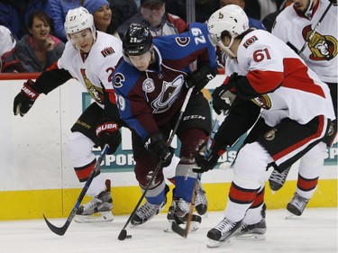 Colorado Avalanche center Nathan MacKinnon, center, tries to clear the puck between Ottawa Senators right wings Curtis Lazar, left, and Mark Stone during the second period of an NHL hockey game Wednesday, Nov. 25, 2015, in Denver.