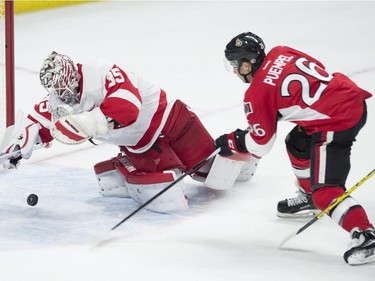 Detroit Red Wings goalie Jimmy Howard turns to dive on a bouncing puck as Ottawa Senators left wing Matt Puempel races to the net during first period NHL action Monday, November 16, 2015 in Ottawa.