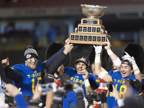 The UBC Thunderbirds' Terrell Davis, centre, raises the Vanier Cup with quarterback Michael O'Connor, left, and Stavros Katsantonis, right, after a 26-23 win over the Montreal Carabins on Saturday, Nov. 28, 2015 in Quebec City.