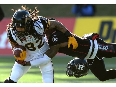 Ottawa Redblacks defensive back Jovon Johnson loses his helmet as he tackles Hamilton Tiger-Cats wide receiver Kealoha Pilares, left, during first half action in the CFL East Division final in Ottawa, Sunday November 22, 2015.