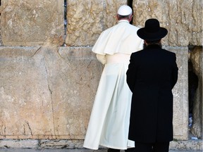 Pope Francis prays at the Western Wall, the holiest place where Jews can pray, as an unidentified Rabbi looks at him, in the old city of Jerusalem, Israel, Monday, May 26, 2014.