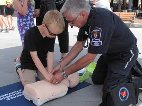 Rocky Galletta, right, of the Ottawa Paramedic Service, teaches a young CPR student in the ByWard Market on Friday, May 29, 2015.
