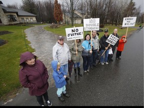 Scott Becker, in baseball cap, is flanked by fellow Emerald Links Community Association members, Perry Deluca, left, and Marc Lamarre, right, along with other concerned residents as they stand in front of Rheal Leroux's house Friday November 13, 2015. Leroux is a former NCC executive who's defied a city bylaw that prohibits filling in the ditch in front of his property.