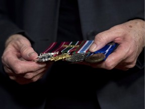 Sheila Fynes holds the medals of her son, Cpl. Stuart Langridge, during a news conference about the Final Report of the Fynes Public Inquiry during a news conference, Tuesday, March 10, 2015 in Ottawa. The medals are (left to right) the Sacrifice medal, and for service in Afghanistan, Peacekeeping and Bosnia.