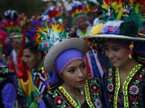 Two girls dressed in traditional Bolivian costumes talks after taking part in a parade organised by Spanish leftist Podemos ('We Can') party as a pre-campaign meeting in Madrid, Sunday, Nov. 22, 2015. During the parade dance folk groups from Bolivia, Peru and Ecuador performed along the streets of the city centre of the Spanish capital.