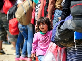 A young girl from Syria holds the hand of an adult while standing in a queue of people waiting to board a train to the border with Serbia, near the town of Gevgelija, on the Greek border. Since July, the rate of refugees and migrants transiting through the country has increased to approximately 2,000 to 3000 people per day, women and children accounting for nearly one third of arrivals.