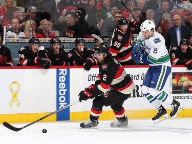 Jared Cowen #2 of the Ottawa Senators gets to the puck ahead of Derek Dorsett #15 of the Vancouver Canucks .