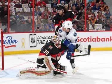 Derek Dorsett #15 the Vancouver Canucks crashes into Andrew Hammond #30 and Jared Cowen #2 of the Ottawa Senators.