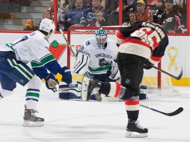 Erik Karlsson #65 of the Ottawa Senators shoots the puck as Ryan Miller #30 of the Vancouver Canucks makes a save with Ben Hutton #27 defending.