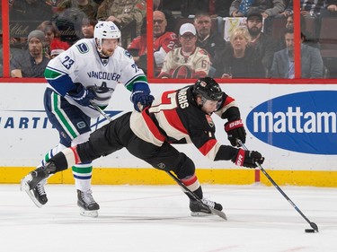 Kyle Turris #7 of the Ottawa Senators makes a backhand pass after being knocked off balance by Alexander Edler #23 of the Vancouver Canucks.