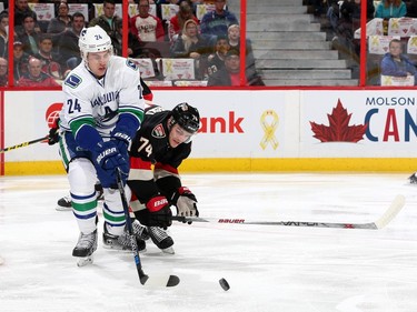 Mark Borowiecki #74 of the Ottawa Senators battles for the loose puck against Adam Cracknell #24 of the Vancouver Canucks.