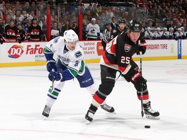 Chris Neil #25 of the Ottawa Senators uses his body to keep the puck from Jared McCann #91 of the Vancouver Canucks.