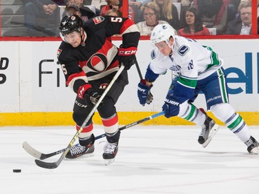 Cody Ceci #5 of the Ottawa Senators skates up ice with the puck against Jake Virtanen #18 of the Vancouver Canucks.