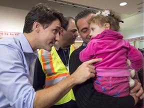 Canadian Prime Minister Justin Trudeau greets 16-month-old Madeleine Jamkossian, right, and her father Kevork Jamkossian, refugees fleeing the Syrian civil war, during their arrival at Pearson International airport, in Toronto, on Friday, Dec. 11, 2015.