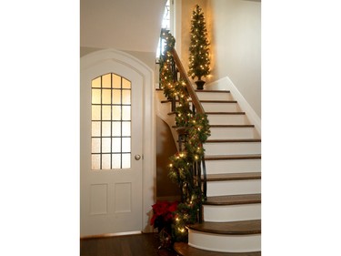 An easy way to add lights, one of several trees and a cascading garland dress up the foyer and stair landing.