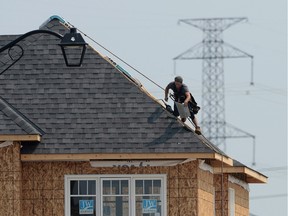 A construction worker shingles the roof of a new home in a development in Ottawa on July 6, 2015. Canada's economy added about 6,600 jobs last month ??? essentially reversing a similar decline in June but not enough to change a national unemployment rate that has been stuck at 6.8 per cent for six months in a row.