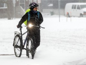 A cyclist pushes her bike along a sidewalk after a heavy snowfall hit the capital region Tuesday.