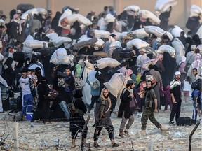 Islamic State members ask people to go back to city center at the Turkish Akcakale crossing gate in Sanliurfa province, on June 13, 2015. Turkey said it was taking measures to limit the flow of Syrian refugees onto its territory after an influx of thousands more over the last days due to fighting between Kurds and jihadists. Under an "open-door" policy, Turkey has taken in 1.8 million Syrian refugees since the conflict in Syria erupted in 2011.