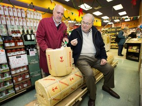 Anthony LoFrisco, 82, right, samples the first scrape of provolone with Joe Nicastro. LoFrisco travelled from Connecticut to see a 1,000-pound provolone cheese delivered to Nicastro's on Merivale Road. When he heard about a similar cheese at Nicastro's last year it reminded him of the 1,000 pound provolone he saw as a boy and had been searching for another for about 70 years.