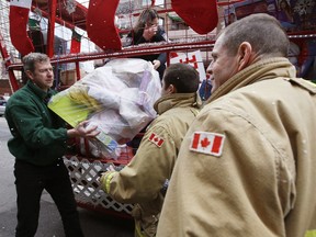 Bob Rainboth, chairman of Santa's Parade of Lights, left, helps haul toys during the toy drop-off from the Ottawa Firefighter Association's Help Santa Toy Parade and Santa's Parade of Lights for the Salvation Army Toy depot Monday December 07, 2015.