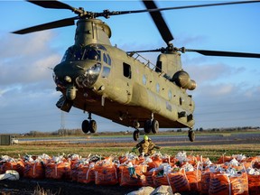 A Royal Air Force Chinook CH47 helicopter airlifts sandbags into a river breach just outside Croston, in northwest England, on Dec. 31, 2015 to protect against flooding.