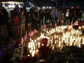 People pay respects at a makeshift memorial site honoring Wednesday's shooting victims, Sunday, Dec. 6, 2015, in San Bernardino, Calif. President Barack Obama vowed Sunday night the United States would overcome a terror threat that has entered a "new phase" as he sought to reassure Americans shaken by recent attacks in Paris and California. (AP Photo/Jae C. Hong)
