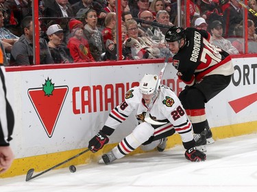 Ryan Garbutt #28 of the Chicago Blackhawks goes down as he reaches for the puck against a defending Mark Borowiecki #74 of the Ottawa Senators.