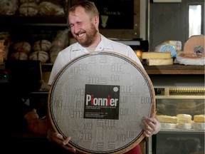 Chris Neil lets out a laugh of exhaustion as he holds  up his prized 32.16-kg (70 lb) wheel of Pionnier, a special cheese released just for Christmas.