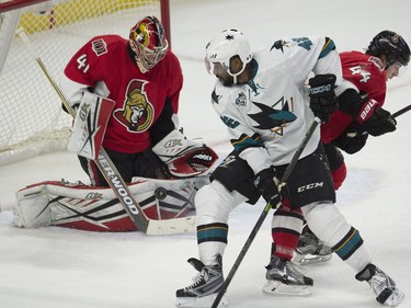 Ottawa Senators goalie Craig Anderson makes a save as San Jose Sharks right wing Joel Ward battles in front of the net with center Jean-Gabriel Pageau during second period NHL action.