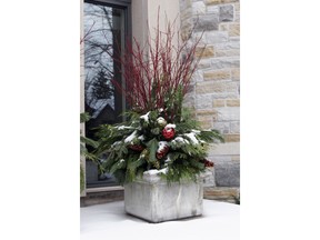 A large urn brimming with red dogwood, fresh boughs and jumbo pine cones welcomes guests for the holidays.