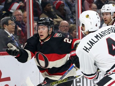 Curtis Lazar, left, of the Ottawa Senators tries to control the puck as he is defended by Niklas Hjalmarsson (4) and Duncan Keith (R) of the Chicago Blackhawks during first period action.