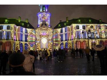 People look at a light and sound show projected on the facade of the city hall of Rennes, western France, on December 22, 2015.  The French company "Spectaculaires", specialists in sound and light, displays each year a light show on the facade of the Rennes city hall for Christmas. They have also projected light and sound shows in Brazil and Vietnam and illuminated the Chartres cathedral, the Notre Dame cathedral and concerts of French singer Francis Cabrel. / AFP / DAMIEN MEYERDAMIEN MEYER/AFP/Getty Images