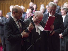 Senate Speaker George Furey is escorted to the Speaker's throne by Senator James Cowan and Senator Claude Carignan after being sworn in during a ceremony in the Senate chamber on Dec. 3, 2015.
