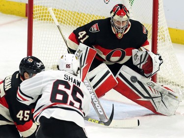 Ottawa Senators goalie Craig Anderson keeps his eye on the puck as Chicago Blackhawks' Andre Shaw (65) and Senators' Chris Wideman (45) battle in front of the net during first period NHL action.