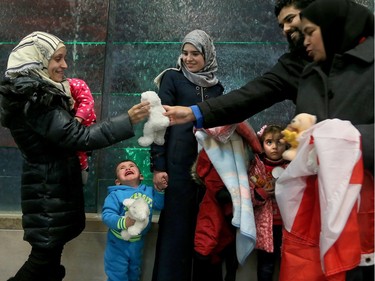 -It all seemed a little too much for one little guy as Kaffa Alwane (left), with her one-year-old daughter, Saloa, accepts a teddy bear from volunteers upon her arrival.  A couple of dozen Syrian refugees, who seemed tired but happy,  arrived at Ottawa's airport Tuesday (Dec. 29, 2015) to a welcoming group of volunteers handing out gifts. The group was taken from the airport in a bus to downtown, but not before feeling the chill of the capital's first winter snowstorm.