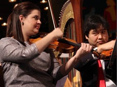 Jessica Linnebach, associate concertmaster with the National Arts Centre Orchestra, performs next to her husband, NAC Orchestra concertmaster Yosuke Kawasaki, during the orchestra's free Christmas FanFair Concert held in the NAC Main Foyer on Sunday, December 13, 2015. Kawasaki can be seen peeking over at their two-year-old daughter, Hanako, who's watching them from the nearby audience.