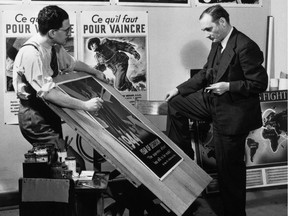 John Grierson, right, the first commissioner (1939-1945) of the National Film Board of Canada, looks at movie posters in this handout photo from 1944.