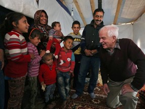 Canadian Minister of Immigration John McCallum, right, speaks with a Syrian family inside their tent, during his visit to a refugee camp in the southern town of Ghaziyeh, Lebanon, Dec. 18, 2015.