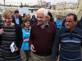Canadian Minister of Immigration John McCallum, center, walks during his visit to a Syrian refugee camp in the southern town of Ghaziyeh, near the port city of Sidon, Lebanon, Friday, Dec. 18, 2015. McCallum was on a one-day visit to Lebanon after which he was to fly to Jordan, also hosting hundreds of thousands of Syrian refugees.