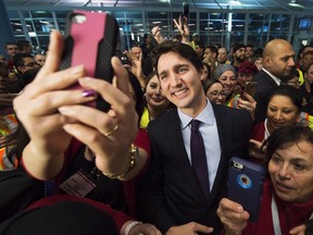 Prime Minister Justin Trudeau poses for selfies with workers before he greets refugees from Syria at Pearson International Airport in Toronto on Thursday night.