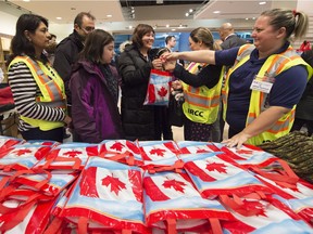 Newly-arrived Syrian refugee Anjilik Jaghlassian, centre, and her family receive winter clothes and other items at Pearson International airport, in Toronto, on Friday, Dec. 11, 2015.