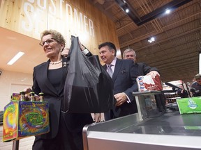 Ontario Premier Kathleen Wynne and Minister of Finance Charles Sousa purchase beer at a Loblaws grocery store in Toronto on Tuesday.