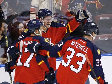 Florida Panthers right wing Logan Shaw, center, is congratulated by center Derek MacKenzie (17) and defenseman Willie Mitchell (33) after he scored his first career NHL goal during the first period.