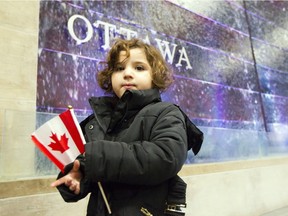 Lyana, the daughter of a refugee family from Syria, holds a Canadian flag after arriving at the Macdonald-Cartier International Airport in Ottawa Tuesday December 22, 2015.