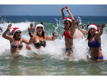 Marlies Noordeloos of the Netherlands, left, Lisa Van De Velde of Belgium, second left, Charlotte Trotter of Britain, second right, and Viktoria Sardarian of Lithuania wear Santa hats while in the surf at Bondi Beach celebrating Christmas Day in Sydney, Australia, Friday, Dec. 25, 2015.