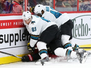 Mika Zibanejad of the Ottawa Senators is buried by Justin Braun (61) and Joel Ward (42) of the San Jose Sharks during first period NHL action.