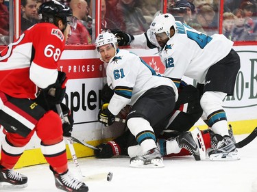 Mika Zibanejad of the Ottawa Senators is buried by Justin Braun (61) ad Joel Ward (42) of the San Jose Sharks as Mike Hoffman takes the puck during first period NHL action.