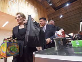 Ontario Premier Kathleen Wynne, left, and Minister of Finance Charles Sousa purchase beer at a Loblaws grocery store in Toronto on Tuesday, December 15, 2015.